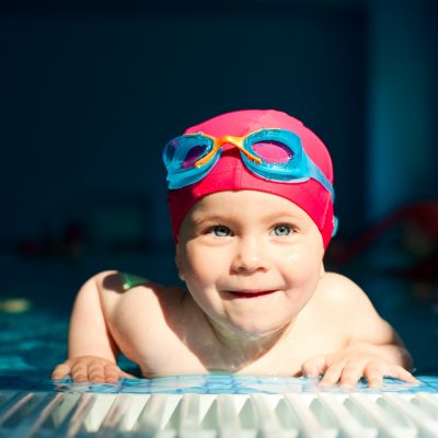 Happy little girl looking out from swimming pool